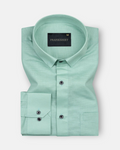A green, long-sleeved, button-down linen shirt with a chest pocket on the left side.