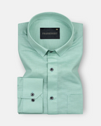 A green, long-sleeved, button-down linen shirt with a chest pocket on the left side.
