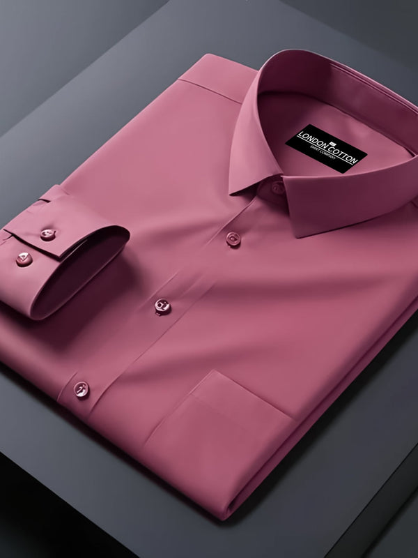 Folded pink dress shirt with a brand label on a dark surface